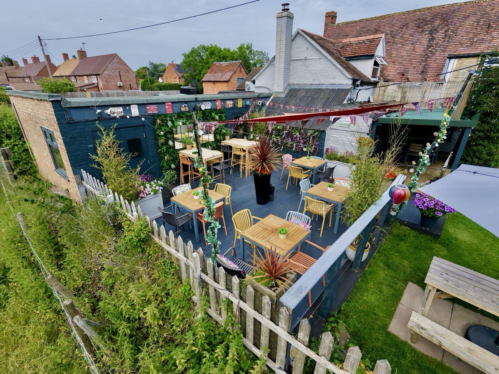 The decked secret garden terrace at The Masons Arms, strung with bunting and festoon lights.