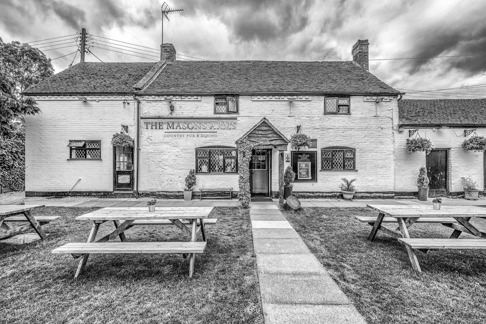 The Masons Arms' whitewashed, half-timbered exterior with picnic tables on the front lawn.